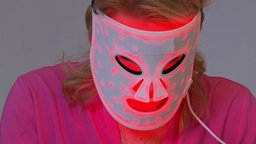 Frau trägt leuchtende LED-Maske.