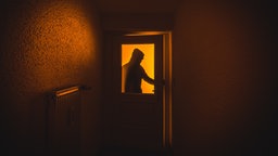 Das Bild ziegt einen Einbrecher an einer Wohnungstür. 