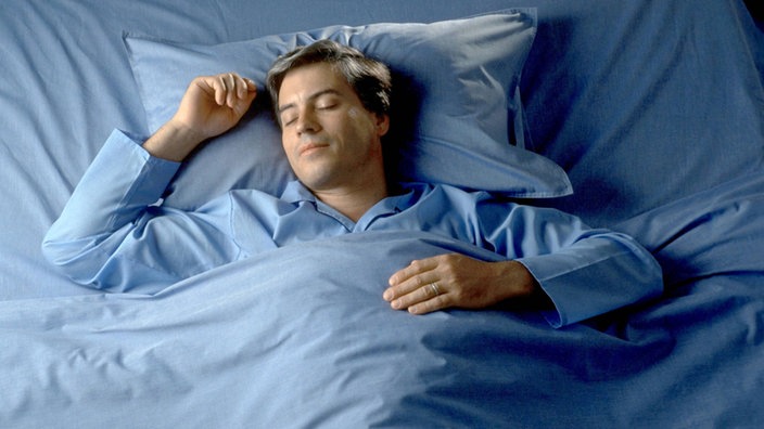 Das Bild zeigt einen Mann, der im Bett liegt und schläft.