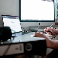 Jemand sitzt am heimischen Schreibtisch am Computer mit zwei Monitoren
