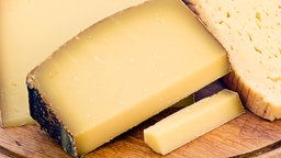 Bergkäse auf einem Brettchen mit Messer.