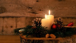 Zwei brennende Kerzen und Weihnachtsdeko.