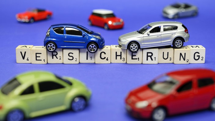 Miniaturautos auf dem Schriftzug Versicherung