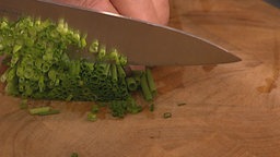 Schnittlauch wird mit dem Messer gehackt