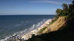 Steilküste mit Baumbestand, davor feinkörniger Sandstrand