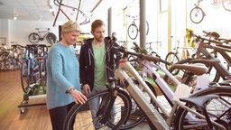 Verkäufer hilft Kundin mit einem E-Bike