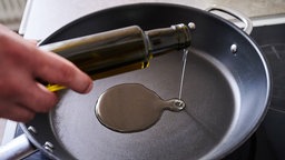 Öl wird in eine Pfanne gegossen