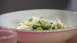 Pasta mit frischen Erbsen, Artischocken und grünem Spargel dekoriert mit Käse