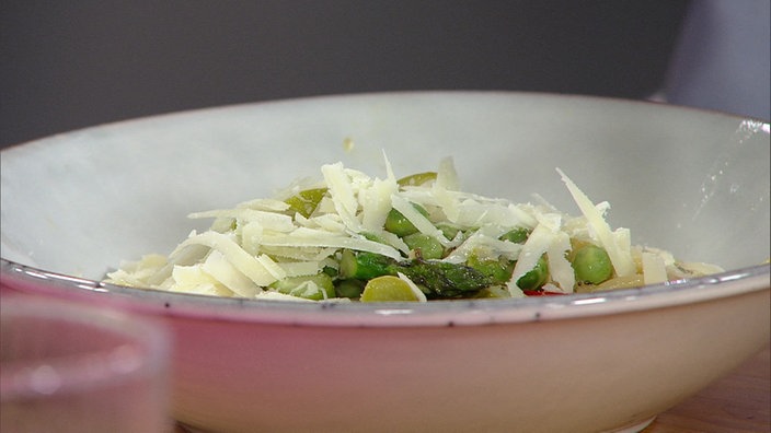 Pasta mit frischen Erbsen, Artischocken und grünem Spargel dekoriert mit Käse