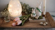 Osterdeko mit Leuchtei, Tulpen, Kerzen und Hasen