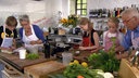 Martina und Moritz sowie zwei Mädchen und ein Junge bereiten in der Küche Speisen zu