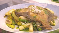 Gebratener Spargel mit gebratenem Fisch auf einem Teller angerichtet