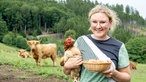 Conny Nebling-Stamm mit einem Huhn im Arm, auf der Weide.