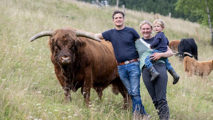 Conny Nebling-Stamm mit ihrem Mann Mario und Söhnchen auf der Weide mit Schottischem Hochlandrind. 
