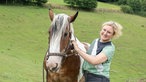 Conny Nebling-Stamm kuschelt mit einem Pferd. 