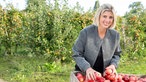 Jessica Joos auf der Obstwiese mit geernteten Äpfeln. 