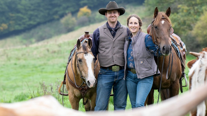 Katharina Deitmers mit ihrem Mann Helge auf der Weide mit Pferden und Longhorn Rindern