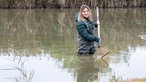 Svenja Viertel steht in einem Fischteich. 
