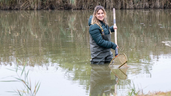 Svenja Viertel steht in einem Fischteich. 