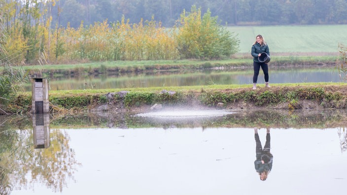 Svenja Viertel steht in einem Fischteich. 