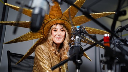 Vicky Just sitzt im Kostüm vor einem Radio-Mikrofon