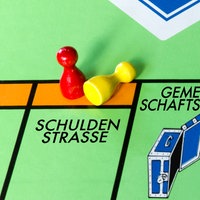 Ausschnitt eines aus Kommunen angepasstes Monopoly-Spielbretts unter anderem mit der "Schuldenstraße"
