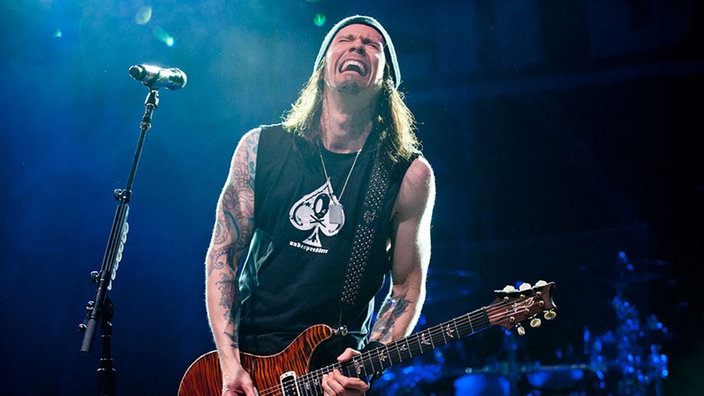 Bandmitglied von Alter Bridge spielt Gitarre und singt dabei mit schmerzverzerrtem Gesicht