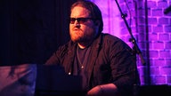 Der Band-Pianist trägt Vollbart und sitzt vor dem Keyboard
