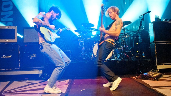 Der Gitarrist und der Bassist von Biffy Clyro spielen sich zugewandt vor dem Schlagzeug.