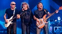 Sänger, Gitarrist und Bassist von Chickenfoot stehen nebeneinander und musizieren zusammen