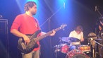 Der Bassist von Daniel Cirera steht im Vordergrund bei Bootleg im August 2006, während im Hintergrund er Drummer am spielen ist.