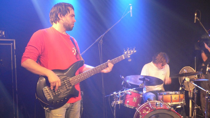 Der Bassist von Daniel Cirera steht im Vordergrund bei Bootleg im August 2006, während im Hintergrund er Drummer am spielen ist.