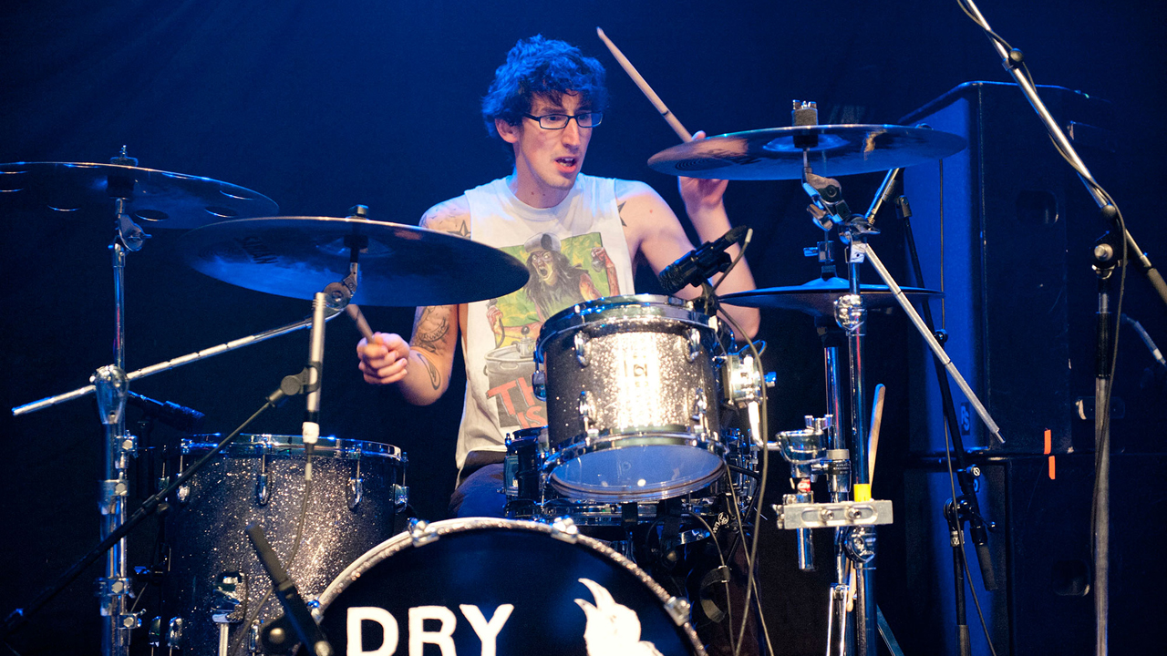 Der Drummer sitzt hinter seinem Schlagzeug