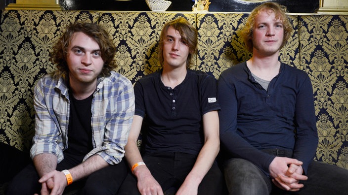 Die Musiker von Birth of Joy: drei junge Männer - schätzungsweise Mitte Zwanzig - klassisch-legere in Jeans und Shirts, mit halblangen, betont ungeschnittenen Haarfrisuren.