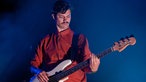 Bassist der Band Efterklang im orangen Hemd spielt und schaut nach unten