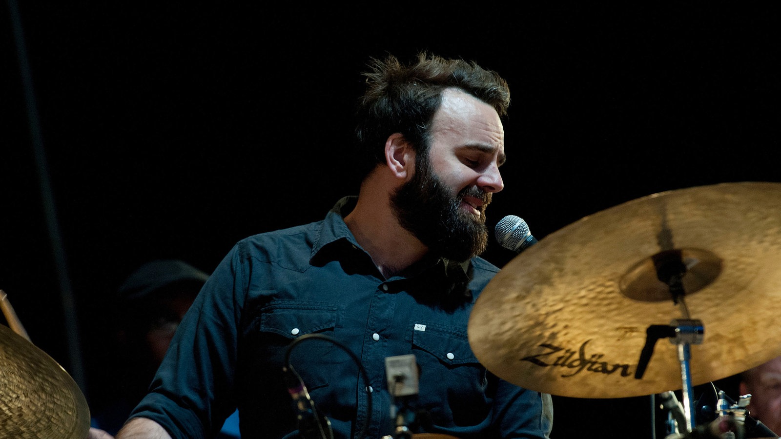 Drummer singt beim Spielen in ein Mikrofon 