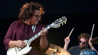 Frontfrau der Alabama Shakes spielt Gitarre und schaut zur Seite, im Hintergrund spielt der Schlagzeuger