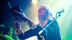 Eine blonde Sängerin der Band Tu Fawning steht auf der Bühne