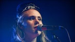 Dies ist eine Portrait Aufnahme von Kate Nash beim Singen mit ihrem Diadem auf dem Kopf.