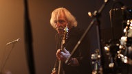 Leo Lyans starrt geradeaus udn spielt Gitarre