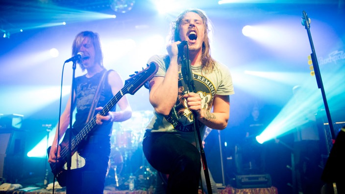 Sänger und Bassist der Band John Coffey stehen nebeneinander und singen Richtung Publikum