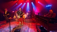 Die Band King King in der Totalaufnahme, die Gesamte Bühne ist mit Teppich ausgelegt, der Sänger trägt einen Schottenrock