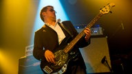 Bassist von King King in einer sehr typischen Bassistenpose, das Gesicht leicht verzogen mit Blick auf das Griffbrett und zurückgelehnt