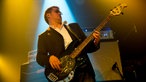 Bassist von King King in einer sehr typischen Bassistenpose, das Gesicht leicht verzogen mit Blick auf das Griffbrett und zurückgelehnt