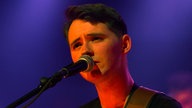 Sänger von New Desert Blues singt und schaut süß am Mikrofon vorbei