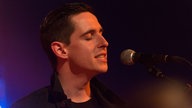 Sänger von New Desert Blues mit geschlossenen Augen vorm Mikrofon