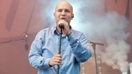 Prinz Pi singt ins Mikro mit Nebel im Hintergrund