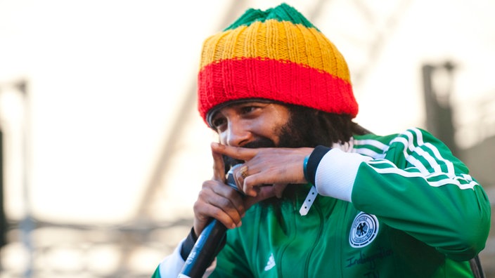 Protoje macht ein zeigefinger Zeichen beim singen