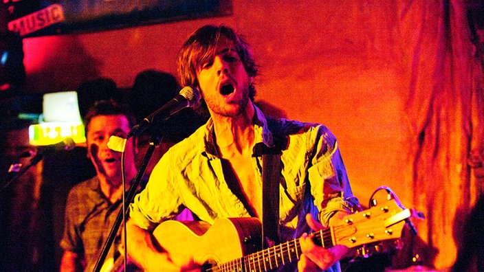 Bandmitglieder von The Tellers spielen Gitarre und singen dabei