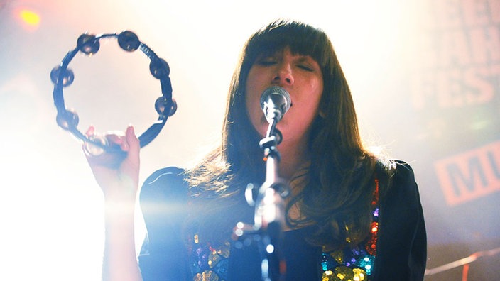 Heidi Lenffer von Cloud Control singt mit geschlossenen Augen und mit einem Tambourin in der Hand